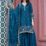 Teal Blue Embroidered Chinon Gharara Set for Eid: A woman posing in a premium 3-piece festive ensemble with intricate gold hand-embroidery, wide-leg gharara, and a matching dupatta.