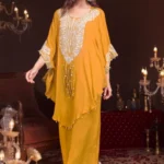 A woman smiling in a 3-piece festive wear set. The kaftan has embroidery on the neckline, long tassels, and worn with matching wide-leg trousers.