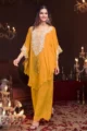 A woman smiling in a 3-piece festive wear set. The kaftan has embroidery on the neckline, long tassels, and worn with matching wide-leg trousers.
