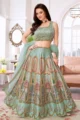 Full view of a woman wearing a mint green choli lehenga set. The lehenga skirt is unique, featuring a digital architectural print of historic Indian archways and structures within patterned panels, combined with fine embroidery and sequin work. The matching mint green choli has mirror work