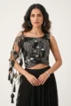 Close-up view of the dense metallic beadwork, sequins, and leaf appliques on the black georgette crop top.