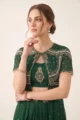Close-up view of the dense silver and gold beadwork, cutdana embroidery, and cape overlay on the emerald green set.