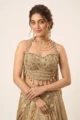 Close-up view of the dense beadwork, cutdana embroidery, and hanging pearl tassels on the beige crepe satin halter choli.