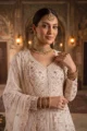 Close-up view of the dense thread embroidery, shimmering sequins, and floral motifs along the center-cut opening of the cream net kurta.